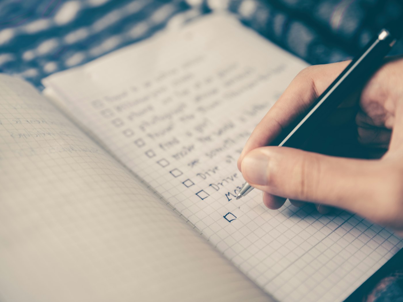 Hand checking off items on a to-do list, representing catching up on bookkeeping backlog